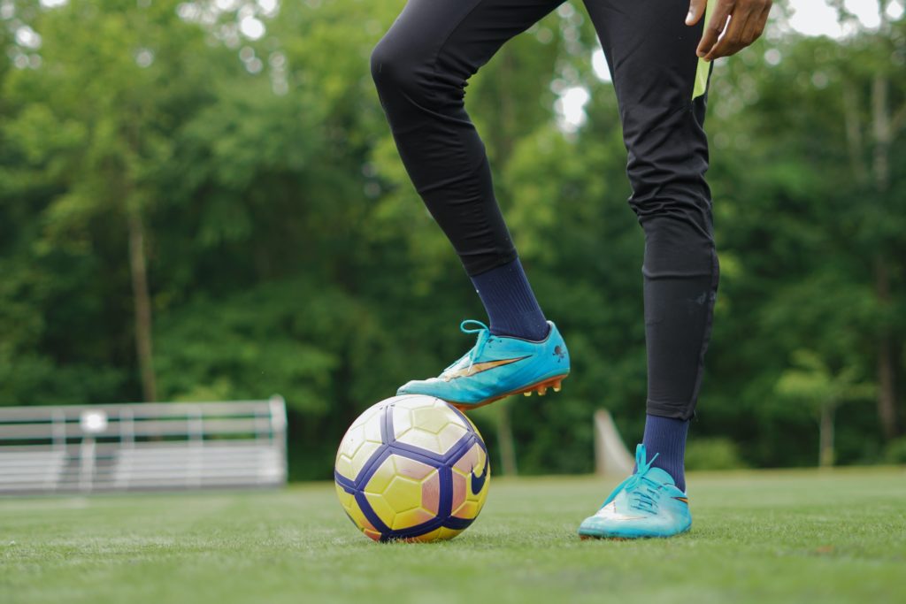 Soccer player resting right leg on top of the ball